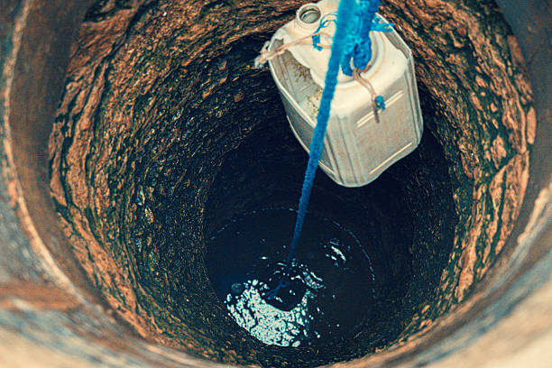 sacando garrafa de un pozo de agua para comprobar el olor